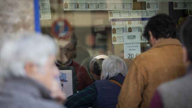 Varias personas hacen cola para comprar lotería en una administración de Sevilla.