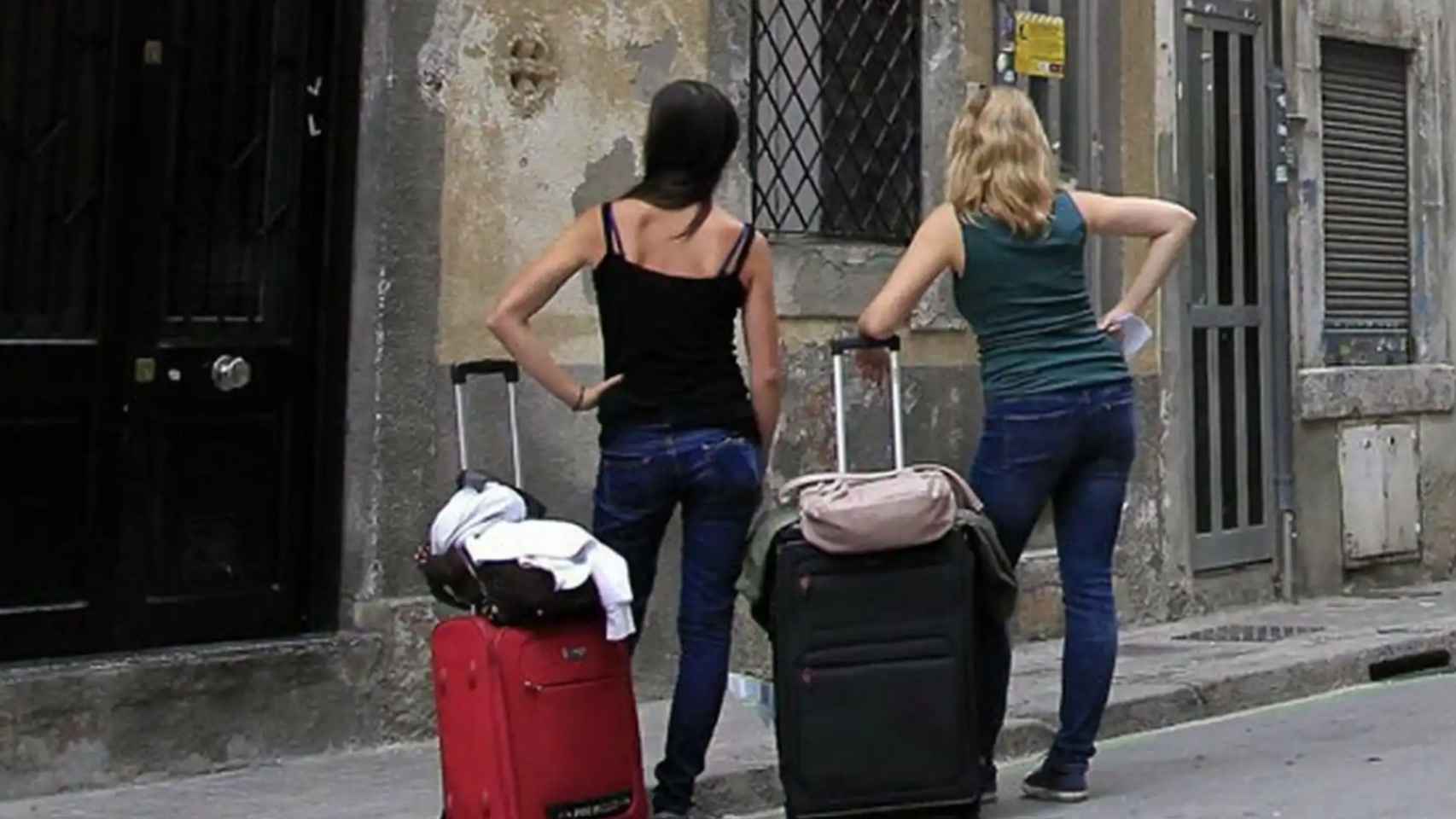 Dos personas esperando frente a un piso turístico.