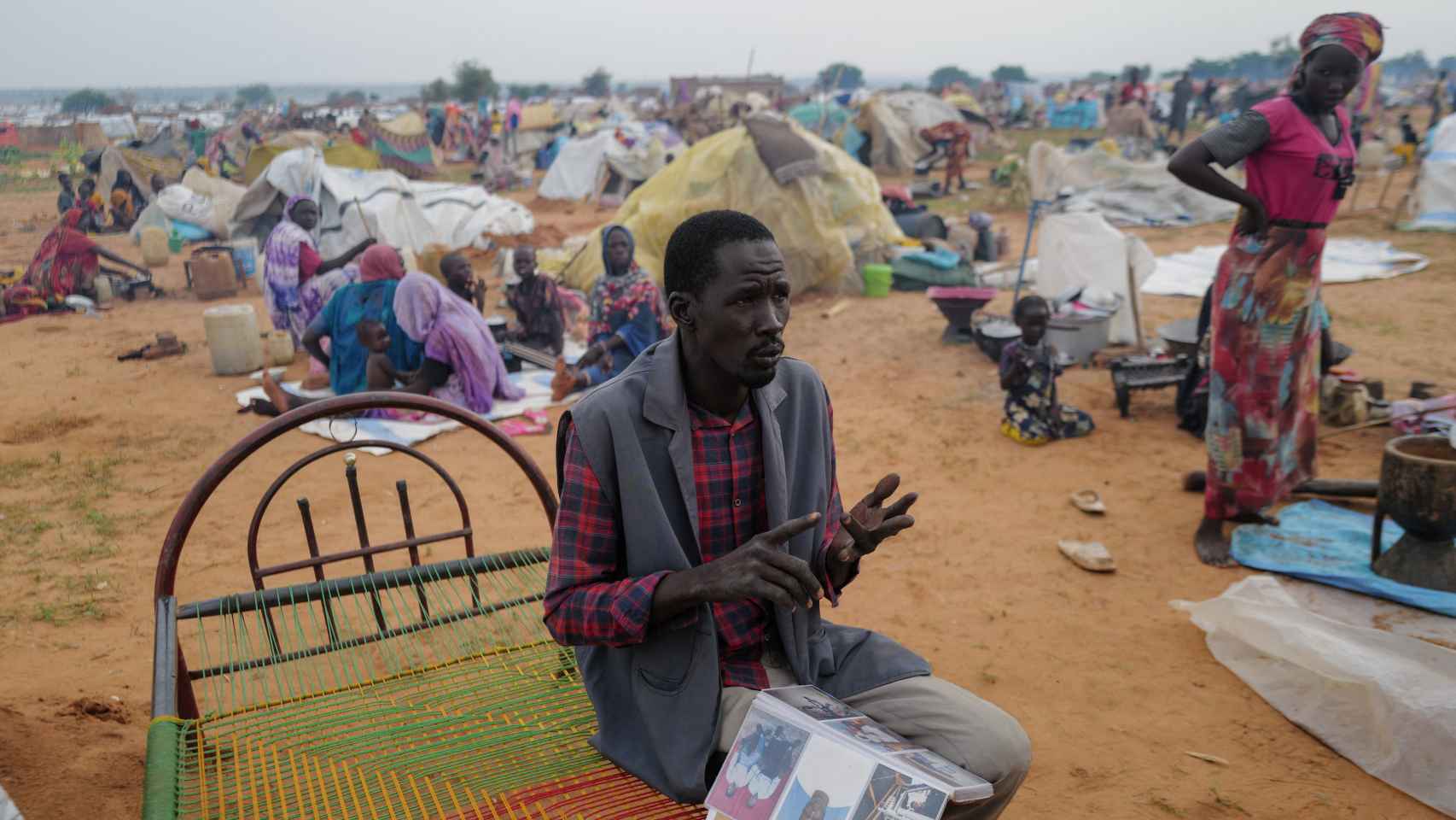 Un hombre sostiene un álbum con fotos de su hijo y su padre, asesinados por las FAR al oeste de Darfur.