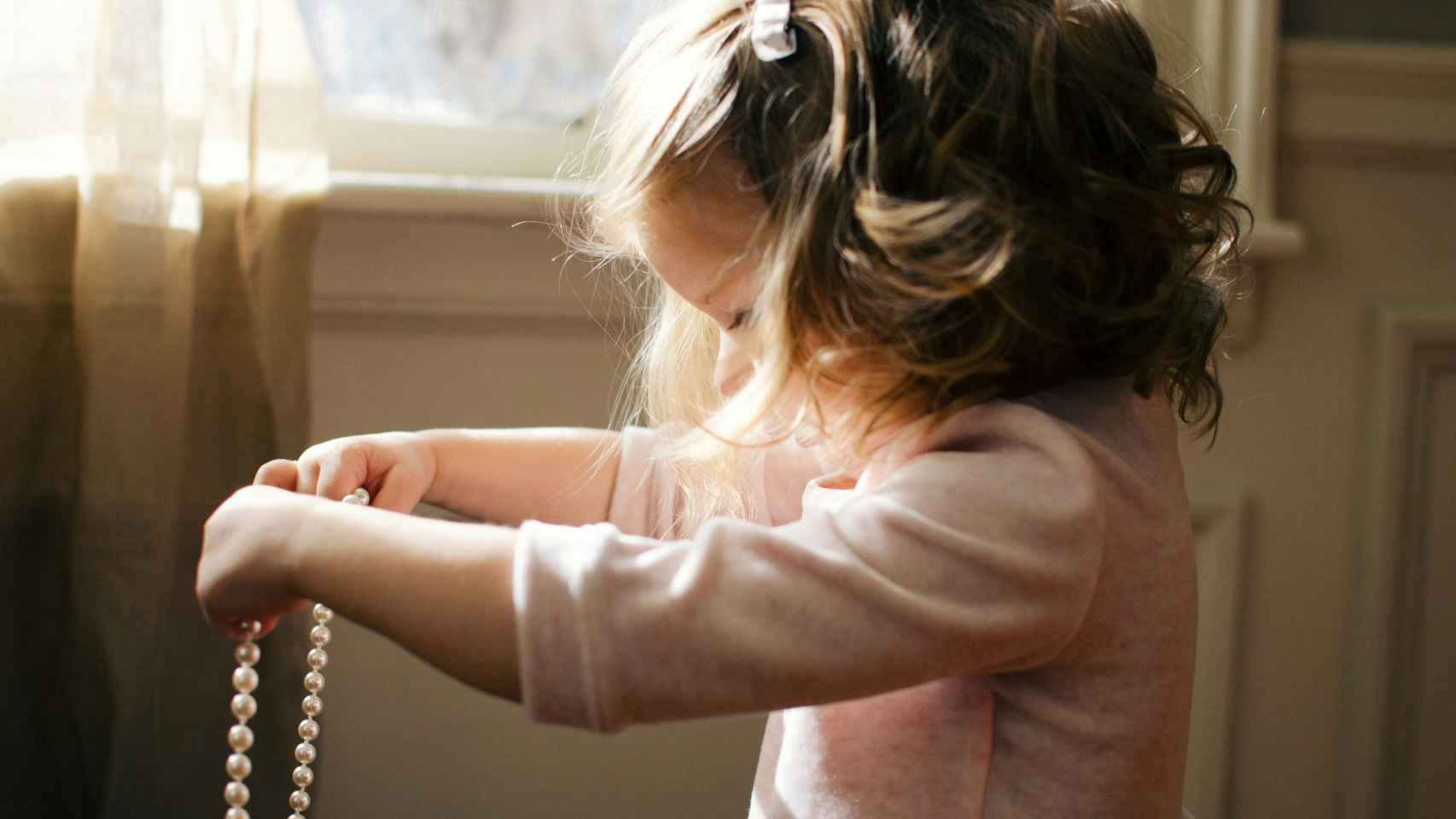 Imagen de archivo de una niña sosteniendo unas joyas.