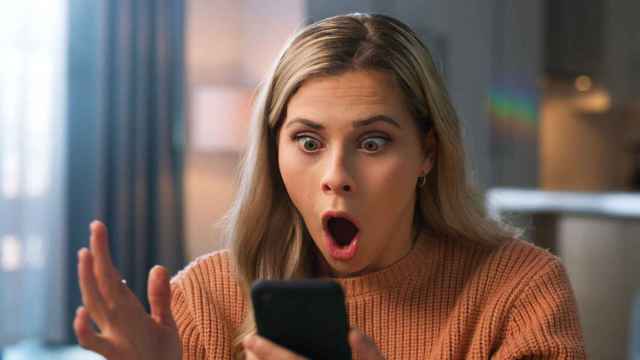 Una mujer pone cara de sorpresa al mirar la pantalla del móvil