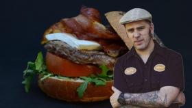 El chef Hermes Castro con una de sus hamburguesas de fondo