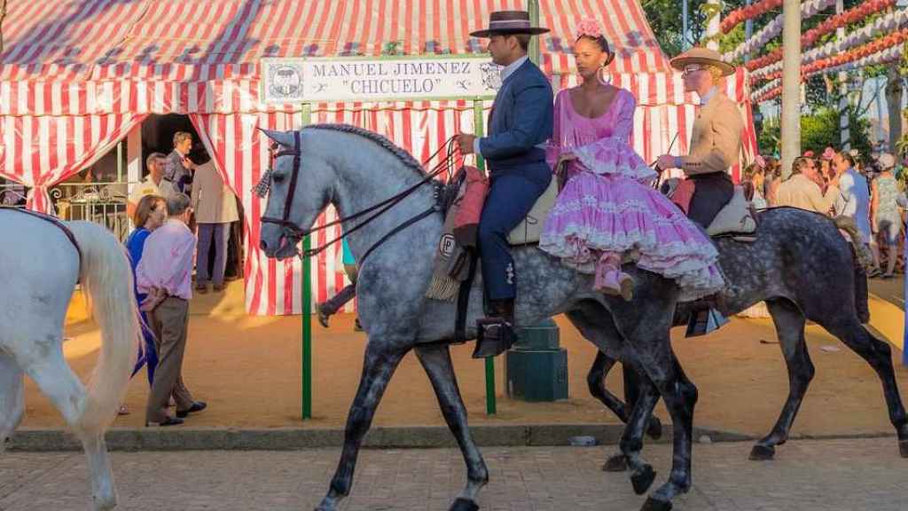 Pareja vestida de flamencos sobre un caballo en la Feria de Granada.