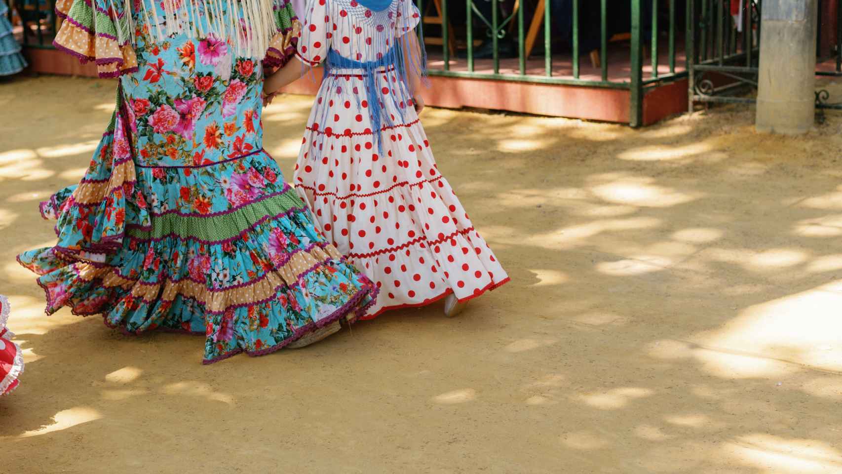 Mujer y niña caminando por la feria vestidas de flamencas.