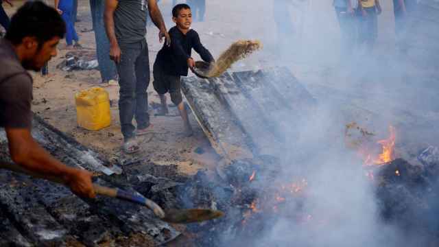 Gazatíes tratan de apagar un fuego en Rafah.