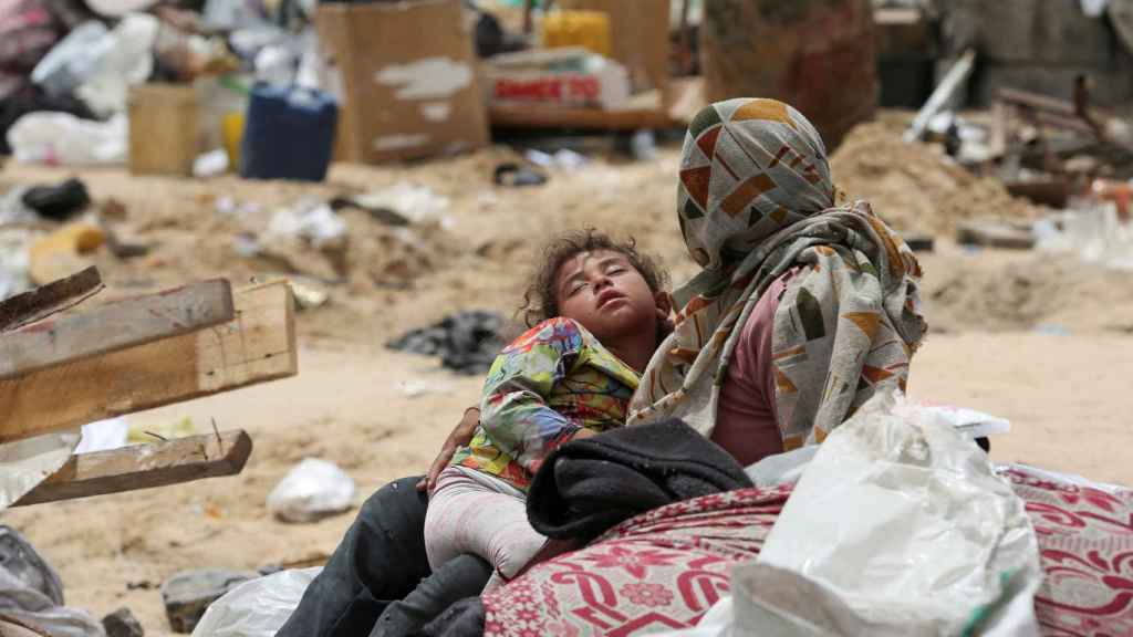 Un niño descansa en los brazos de su madre mientras huyen de Rafah, este martes.