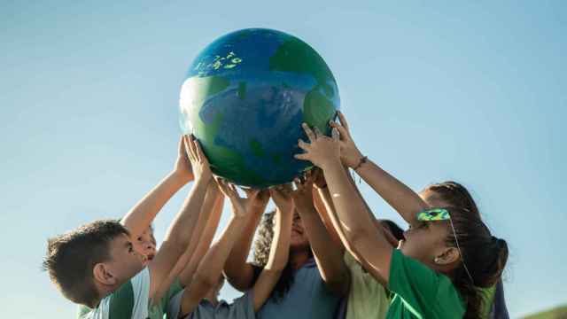 Imagen de archivo de niños sosteniendo una maqueta del planeta.
