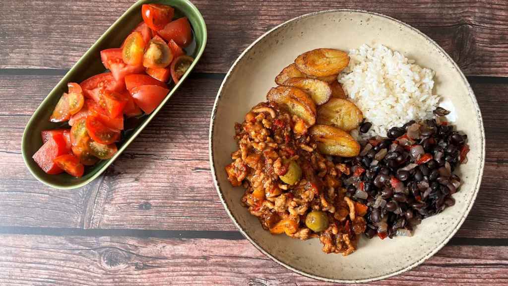 Arroz con frijoles, picadillo y plátano frito con ensalada de tomate.