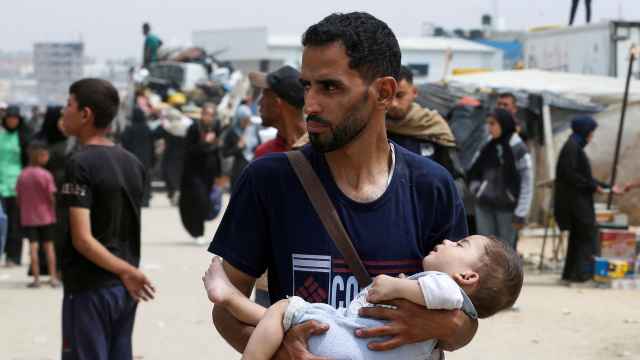Un hombre carga a un niño durante una operación militar israelí, en Rafah.