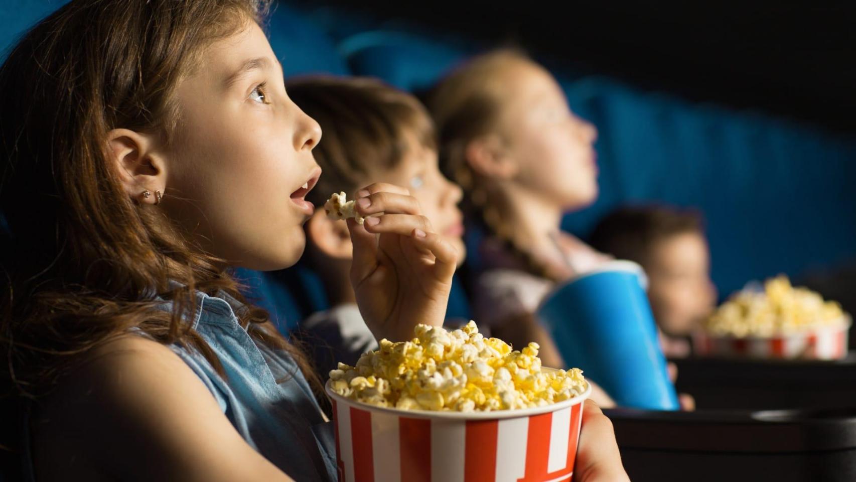 Una niña come palomitas en el cine