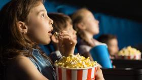 Una niña come palomitas en el cine