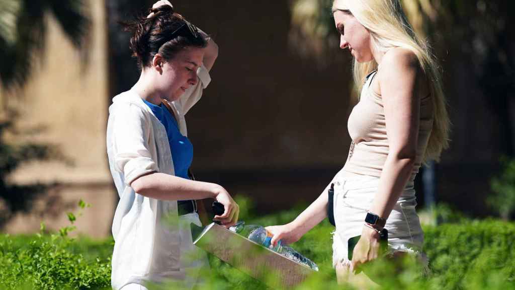 Dos mujeres llenan una botella de agua para hidratarse ante el calor en Málaga.