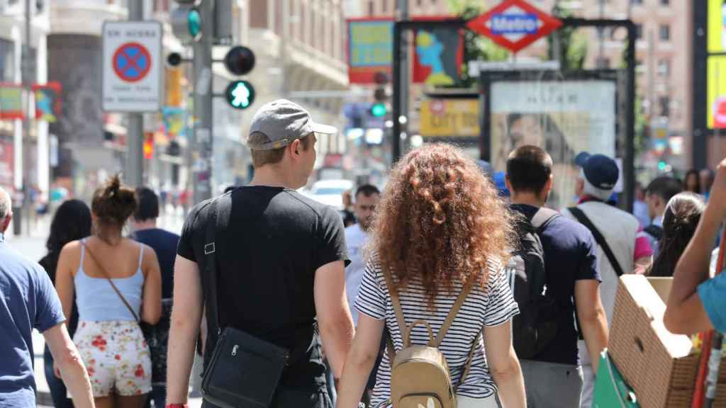 Una pareja cruza de la mano un paso de peatones de la Gran Vía de Madrid.