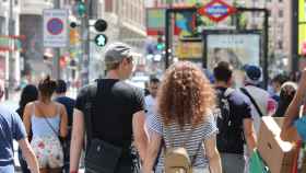 Una pareja cruza de la mano un paso de peatones de la Gran Vía de Madrid.