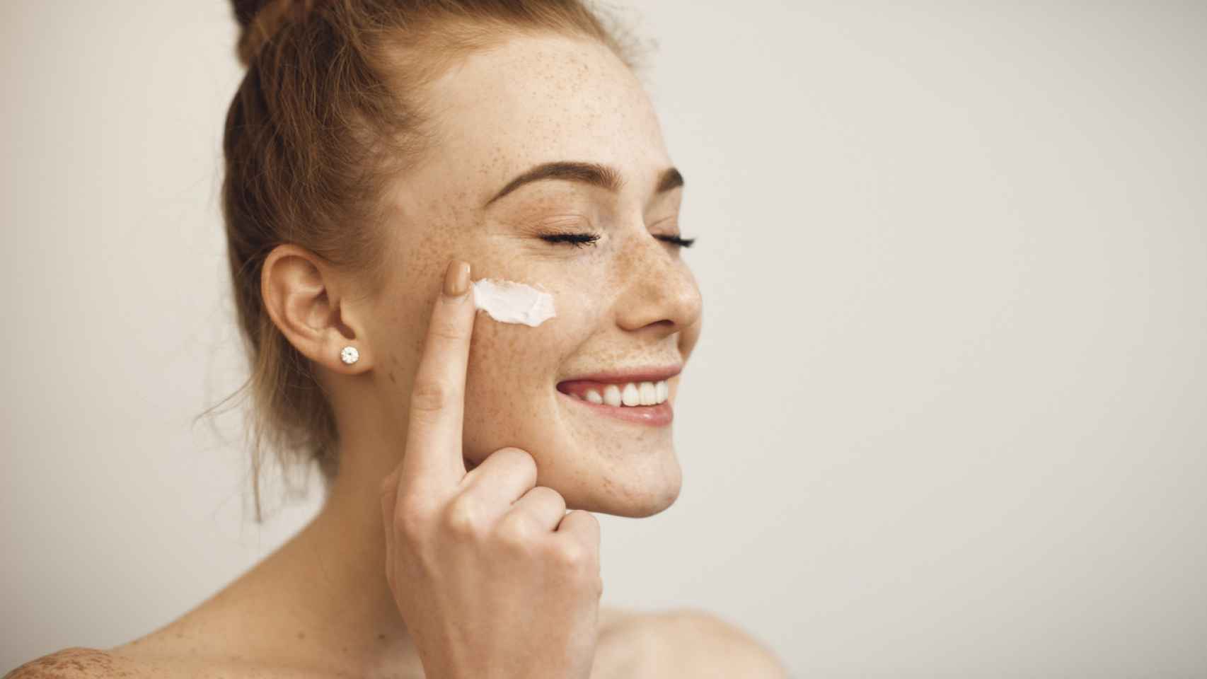 Mujer con manchas y aplicándose una crema facial.