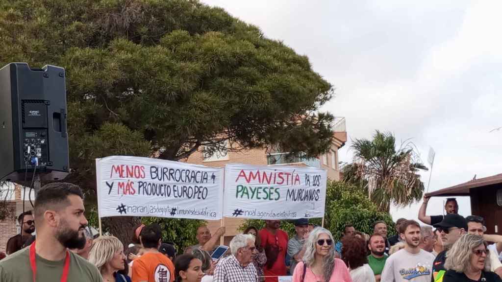 Un pequeño grupo de personas, este viernes, con pancartas de protesta en el acto del PSOE en Los Alcázares.