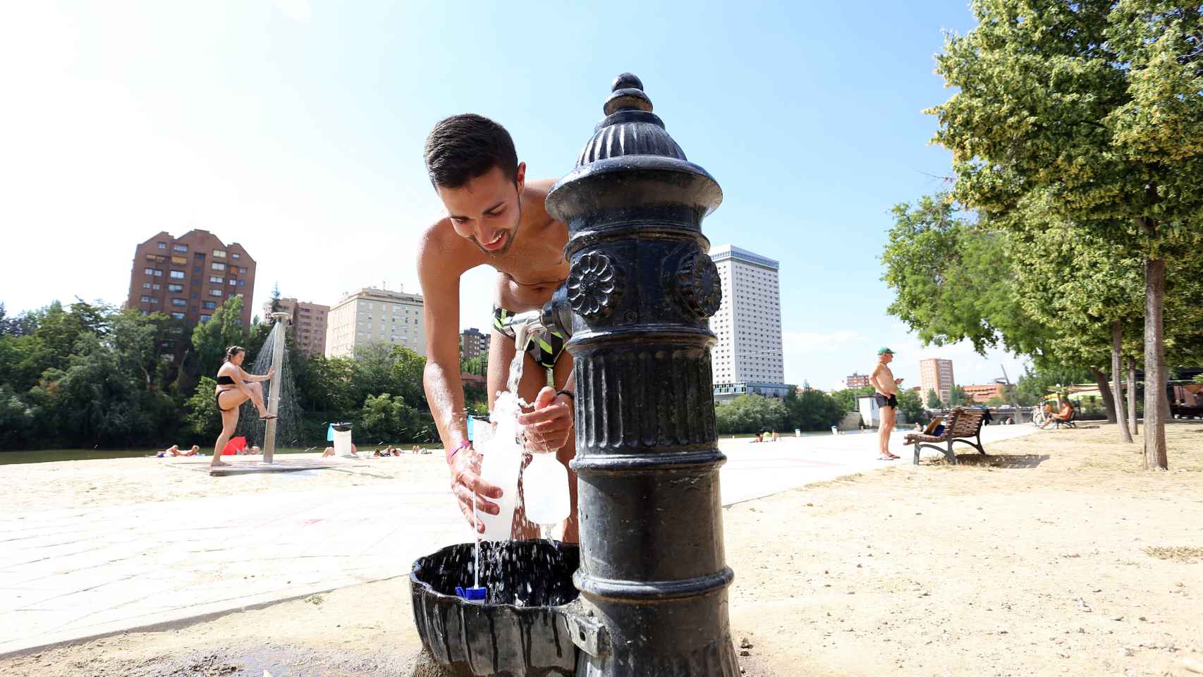 Un hombre llenando la botella de agua en la playa de Las Moreras