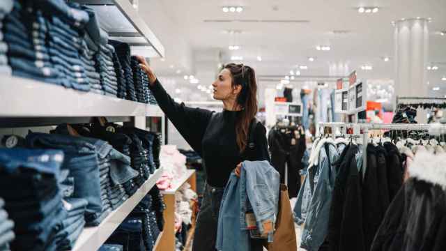 Una mujer mira prendas en una tienda.