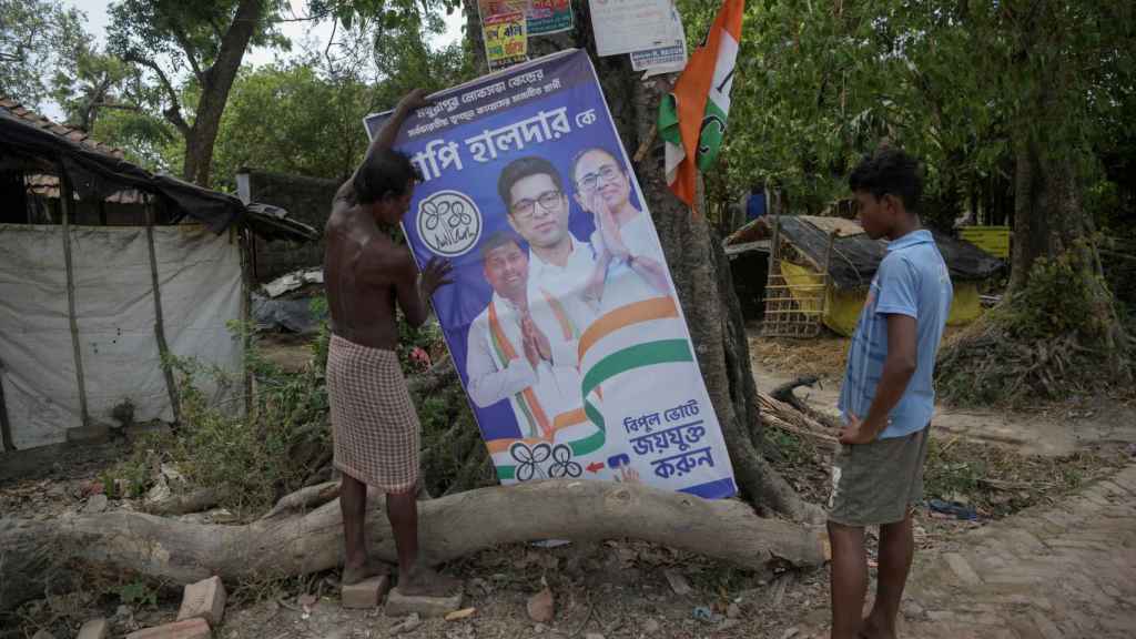Un hombre instala un cartel con líderes y candidatos del All India Trinamool Congress, un partido político regional, para las elecciones generales, a 18 de mayo de 2024.