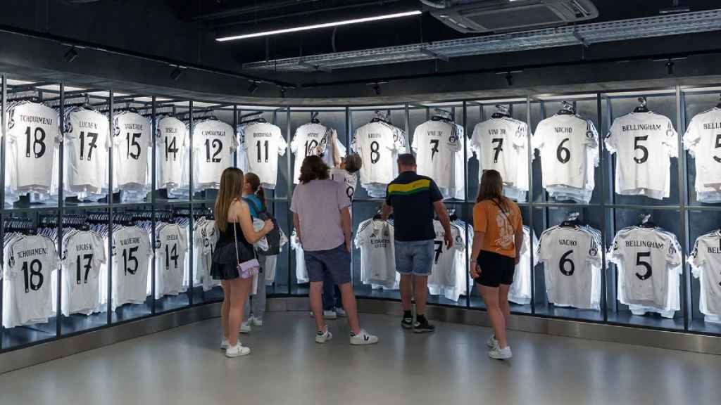 Aficionados del Real Madrid viendo camisetas del club blanco en la nueva tienda del Santiago Bernabéu.