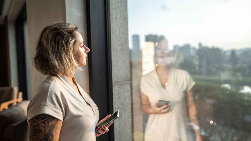 Mujer con aspecto preocupado mirando por la ventana.