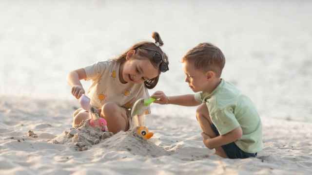 Dos niños jugando con la arena de la playa.