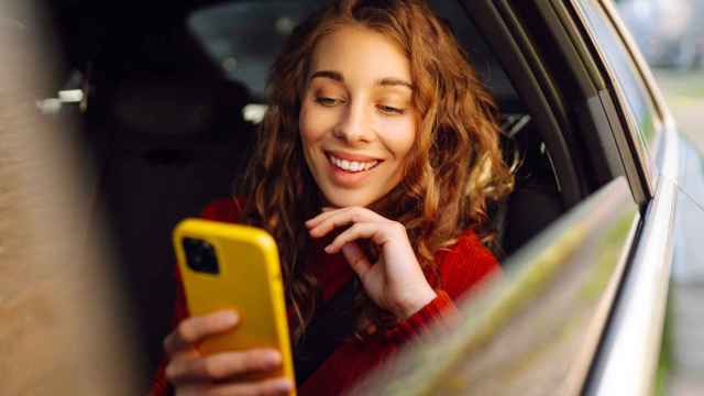 Mujer sonriente con el teléfono móvil mientras viaja en coche.