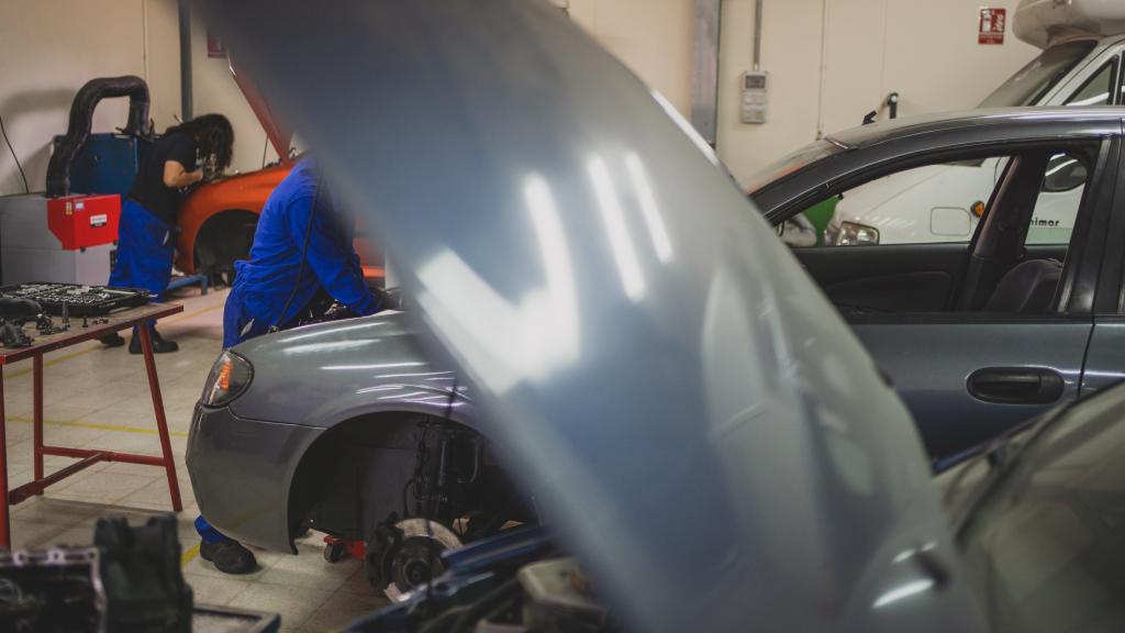 Dos de los jóvenes en prácticas en el taller de automoción en el Centro de Menores Teresa de Calcuta.