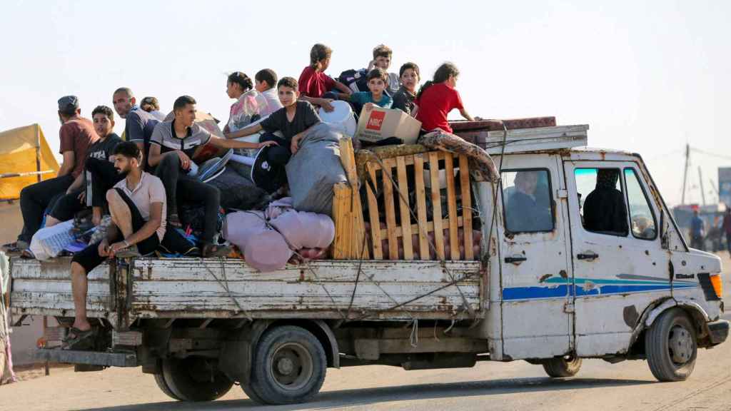Niños y adolescentes se trasladan en un camión en plena zona de conflicto.