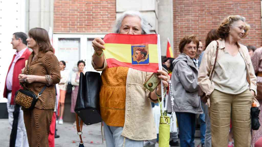 Mujer sostiene bandera de España con Franco durante el rezo en Ferraz