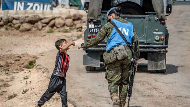 Una soldado española de la misión de la ONU en El Líbano se choca la mano con un niño de ese país.