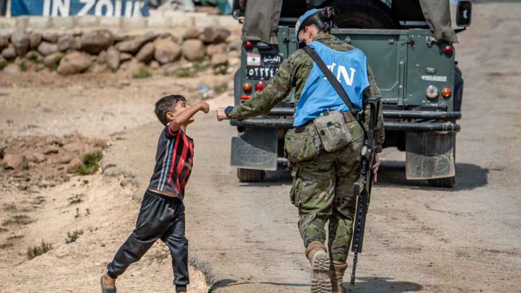Una soldado española de la misión de la ONU en El Líbano se choca la mano con un niño de ese país.
