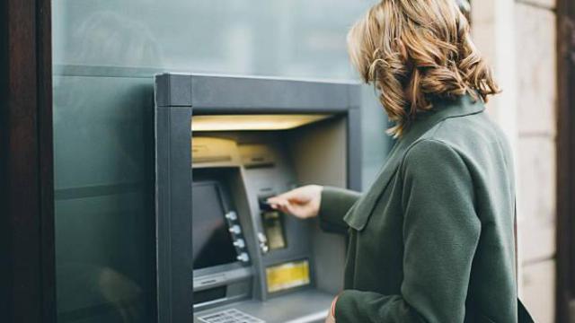 Una mujer saca dinero de un cajero automático.