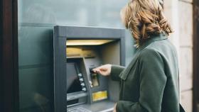 Una mujer saca dinero de un cajero automático.