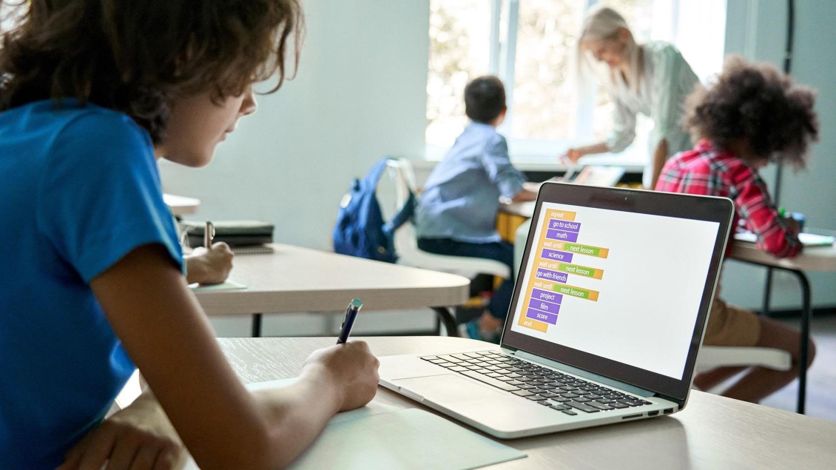 Niño en un aula con un ordenador.