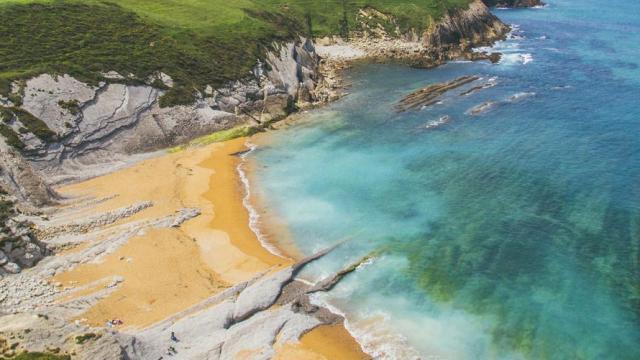 Playa de aguas cristalinas y rodeada de acantilados en la costa norte de España.