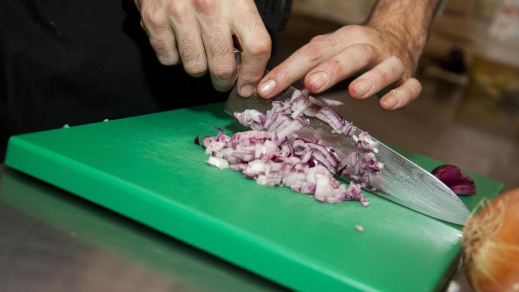 Un cocinero picando cebolla.