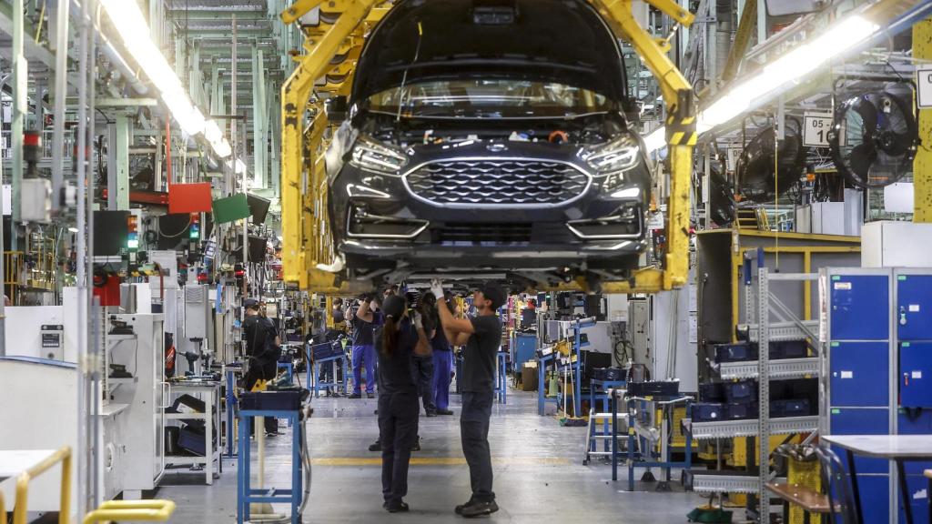 Dos trabajadores con un vehículo de la fábrica de Ford en Almussafes en una imagen de archivo