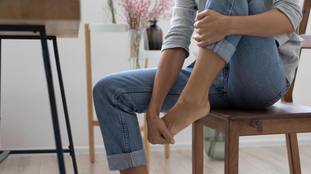 Mujer con dolor de pies en una silla.