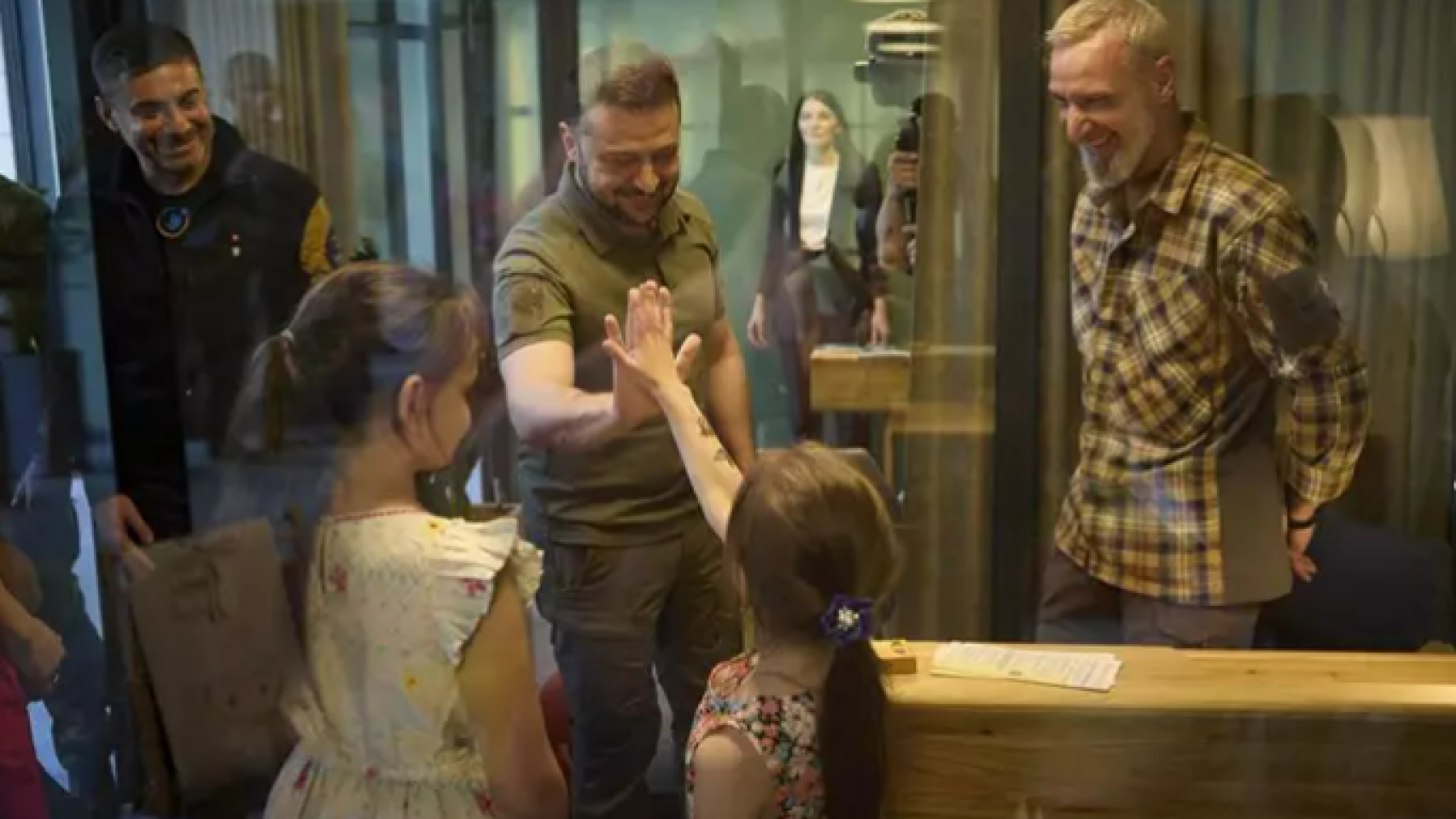 El presidente de Ucrania, Volodimir Zelenski, saluda a unos niños.