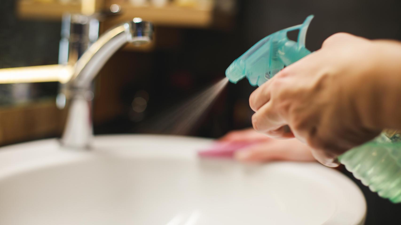 Una mujer limpiando un baño.