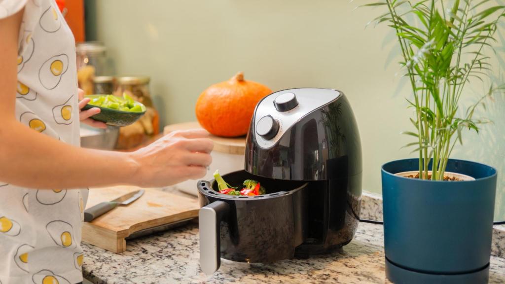 Mujer cocinando verduras en la freidora de aire.