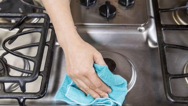 Imagen de una persona limpiando una cocina de gas.