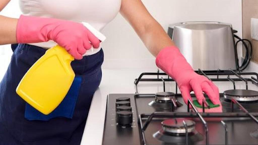 Imagen de archivo de una persona limpiando la cocina de gas.