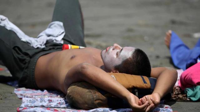 Un joven toma el sol en una playa española.