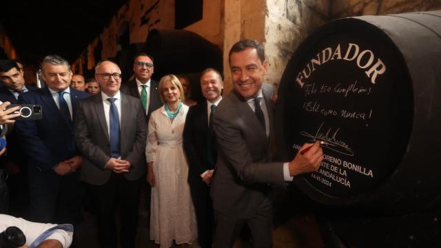 El presidente de la Junta de Andalucía, Juanma Moreno, firma en una de las botas de bodegas Fundador.