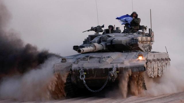 Soldados sostienen una bandera de Israel a bordo de un tanque cerca de la frontera con Gaza.