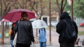 Imagen de archivo de gente con paraguas por lluvia