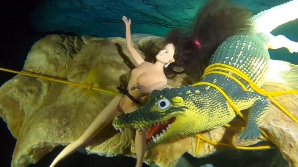 Muñeca 'Barbie' mordida por un cocodrilo de plástico en el cenote Dos Ojos.