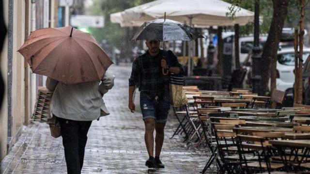 Dos personas con paraguas por Madrid.
